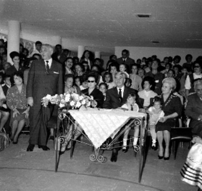 Niños con trajes regionales acompañados por adultos, durante la clausura de cursos en la guarderia de la STPS