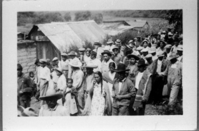 Campesinos caminan en hilera en calle de poblado