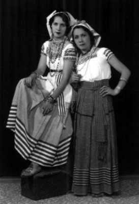 Par de mujeres con trajes folclóricos posan de pie, retrato