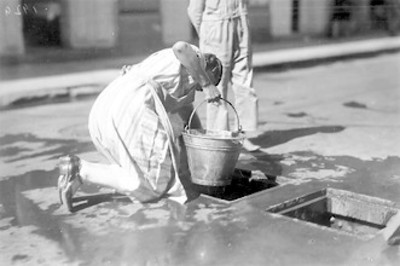 Mujer sacando agua de una alcantarilla debido a la falta de agua
