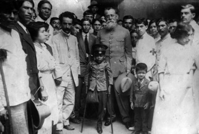 Carranza en compañía de niño con muletas y otras personas, retrato de grupo