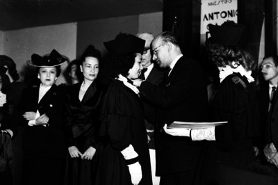 Maestra pronunciando discurso en presencia de Carlos Obregón Santacilia durante una graduación de alumnos
