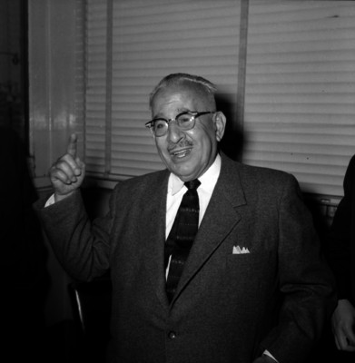 Agustín Olochea Avilés, secretario de la Defensa Nacional haciendo ademanes mientras dialoga con funcionarios