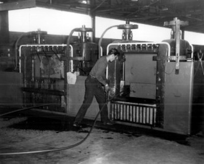 Obrero introduce una tira metálica a un máquina industrial