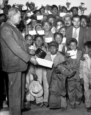 Vidal M. Chavez entrega ropa y zapatos a un niño voceador