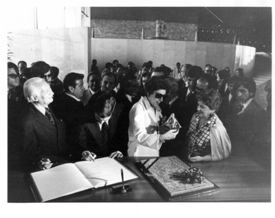 Adolfo Suárez firma el libro de visitas del museo mientras su esposa recibe una figura de cerámica