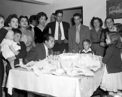 Hombre sopla velas de un pastel durante fiesta familiar