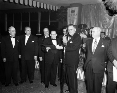 Ejecutivo entrega reconocimiento a un hombre durante convención de la empresa Ford