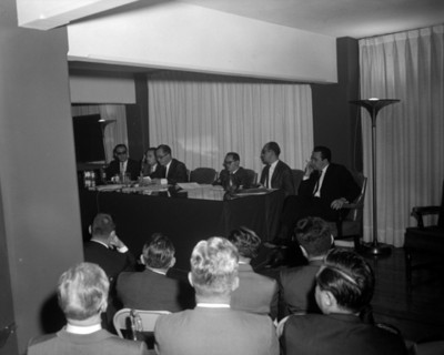 Hombres en mesa directiva durante convención de contadores
