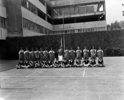 Estudiantes y maestra en patio de escuela, retrato de grupo