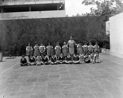Estudiantes y maestra en patio de escuela, retrato de grupo