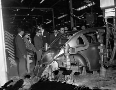 Ejecutivos observan carrocería de un automóvil en una fábrica