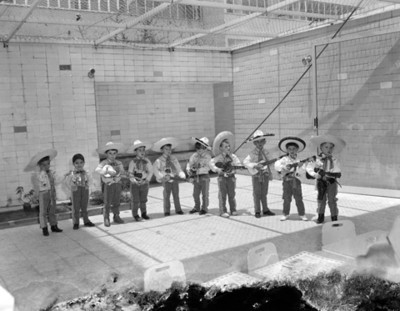 Niños con trajes de mariachis y guitarras durante festival escolar