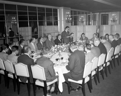 Hombre lee documento a los asistentes a banquete en un salón