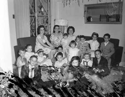 Niños y mujeres en la sala de una casa, retrato de grupo