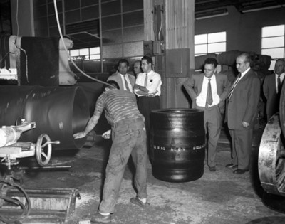 Hombres observan a obrero trabajar durante visita a instaleción industrial