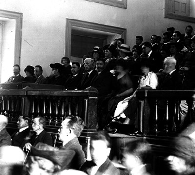 Adolfo de la Huerta acompañado de otras personas, presiden el concurso de voces en el salón de Actos del Museo Nacional