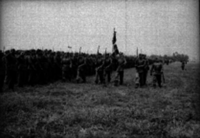 Militares haciendo honores a la bandera en un campo