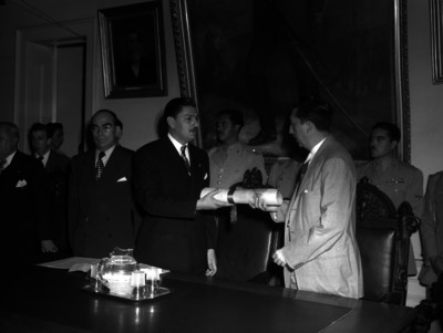 Miguel Alemán Valdés recibe documentos de manos de un funcionario