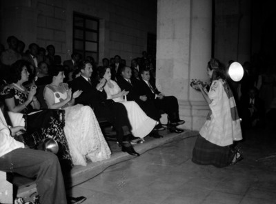 Miguel Alemán Valdés y Beatriz Velasco de Alemán observando a una modelo vestida con traje regional