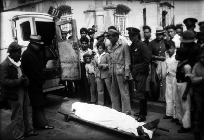 Gente observando el cadáver de una persona en una camilla