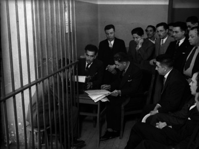 Agentes del Ministerio Público interrogando a un detenido en barandillas
