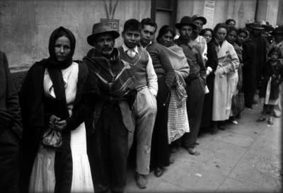 Fila de indigentes y de personas de clase media junto de un muro