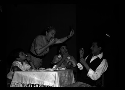 Tulio Jiménez Ponce con varios actores sentados a la mesa durante una obra teatral