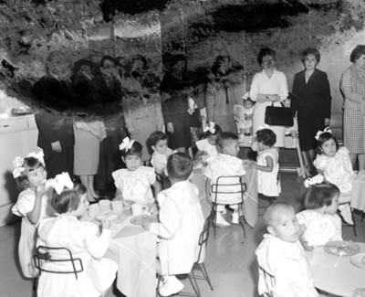Eva Samano de López Mateos y mujeres observan a niños en comedor de INPI
