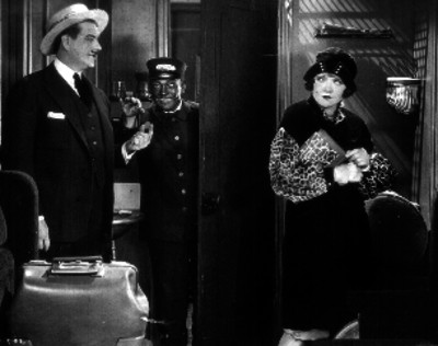 Pareja entra a una habitación del hotel acompañados de un botones negro, escena de película