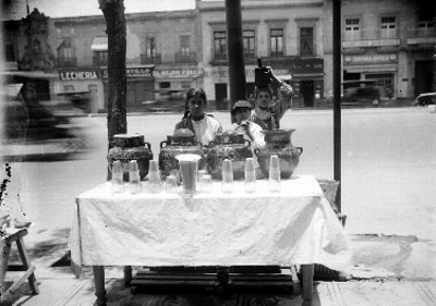 Niños despachan puesto de aguas frescas sobre la banqueta