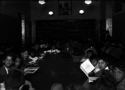 Niños consultan material en biblioteca escolar