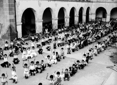 Niños práctican una tabla gimnástica en el patio de una escuela
