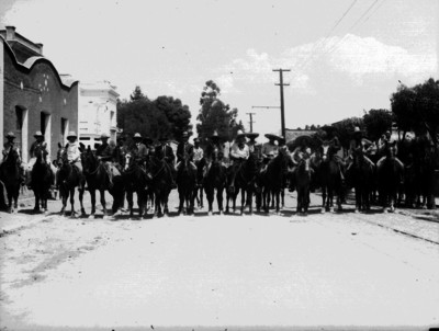 Charros y hombres a caballo en una calle, retrato de grupo