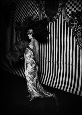 Actiz posa de pie con vestido largo satinado y un abanico de plumas, retrato