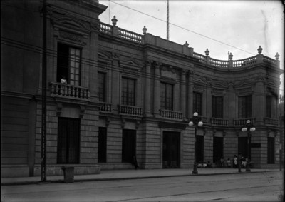 Personas frente a la fachada de la fábrica de cigarros "Tabacalera Mexicana S. A." en la calle de "Puente de Alvarado"