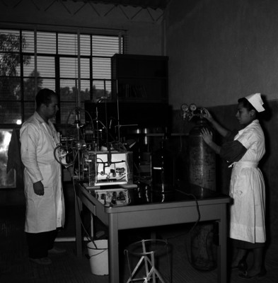 Enfermera controla tanque de gas mientras laboratorista toma mediciones