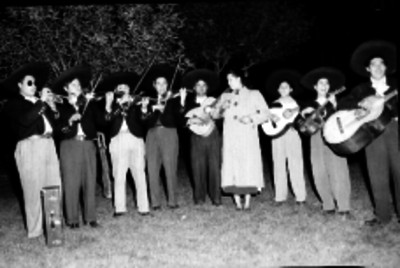 Mujer cantando acompañada de un mariachi