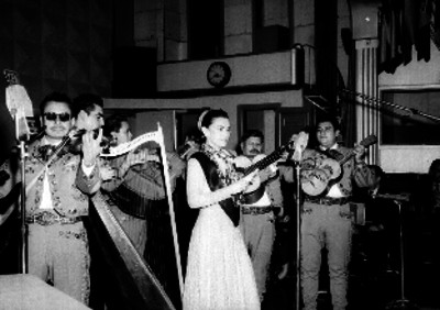 Mujer cantando acompañada por un mariachi