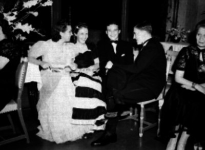 Hombres y mujeres platicando durante un baile de gala