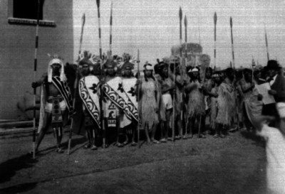 Personas con trajes folclóricos prehispánicos en una calle, retrato de grupo