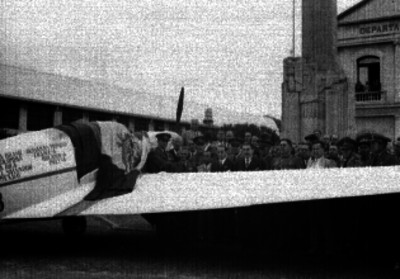 Roberto Fierro, funcionarios y otros militares junto a un avión cubierto con la bandera nacional