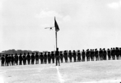 Avión sobrevolando a militares formados
