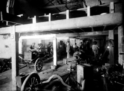 Trabajadores y piezas de autos en un taller automotríz