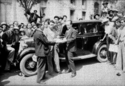 Funcionario entregando documentos a un hombre junto a un automóvil en una calle
