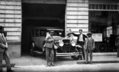 Hombres junto a un auto en la entrada de un taller mecánico