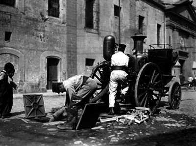 Bomberos con bombas de vapor sacando el agua de una alcantarilla