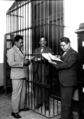 Agentes del Ministerio Público leyendo un acta de proceso penal ante un detenido