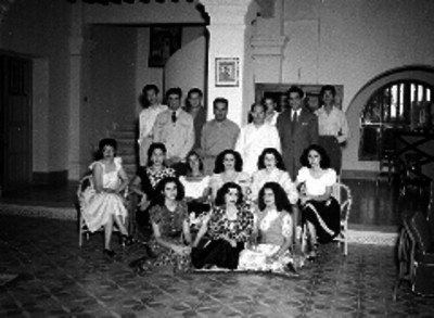 Javier Rojo Gómez acompañado de periodistas y mujeres en una sala, retrato de grupo