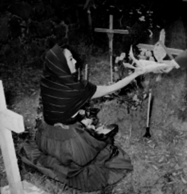 Mujer coloca ofrenda en una tumba